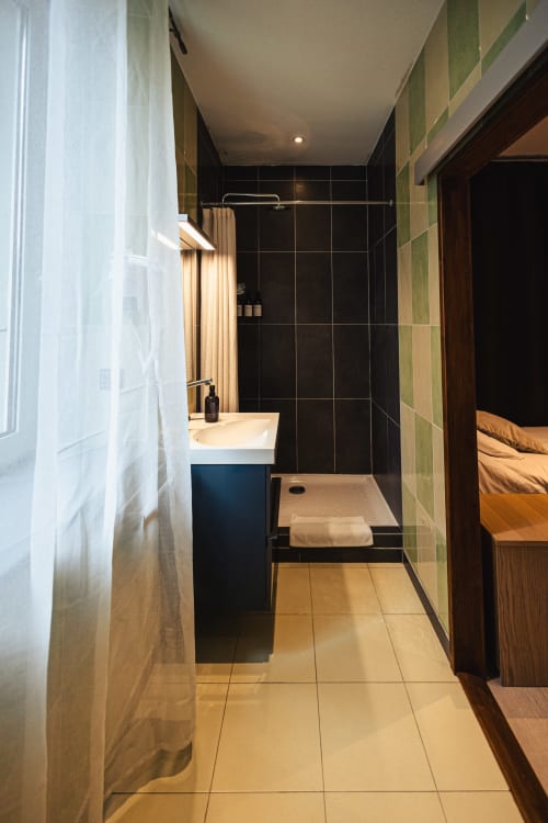 Salle de bains moderne à l'hôtel Savoy avec douche carrelée noire, vasque bleue et carrelage beige au Bourget-du-Lac