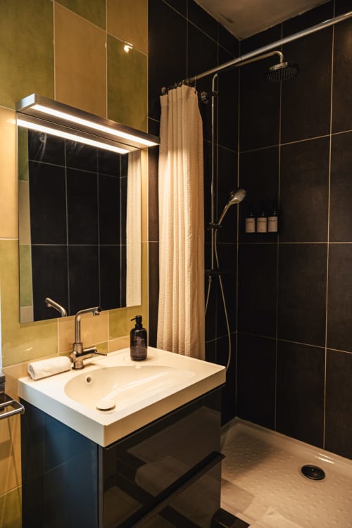 Salle de bains moderne du Savoy Hôtel avec carrelage noir, miroir éclairé, douche pluie et sol chauffant au Le