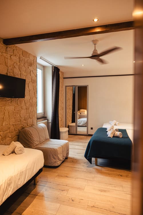 Spacieuse chambre familiale au Savoy Hôtel avec murs en pierre, lit, coin salon, TV écran plat et parquet à Le