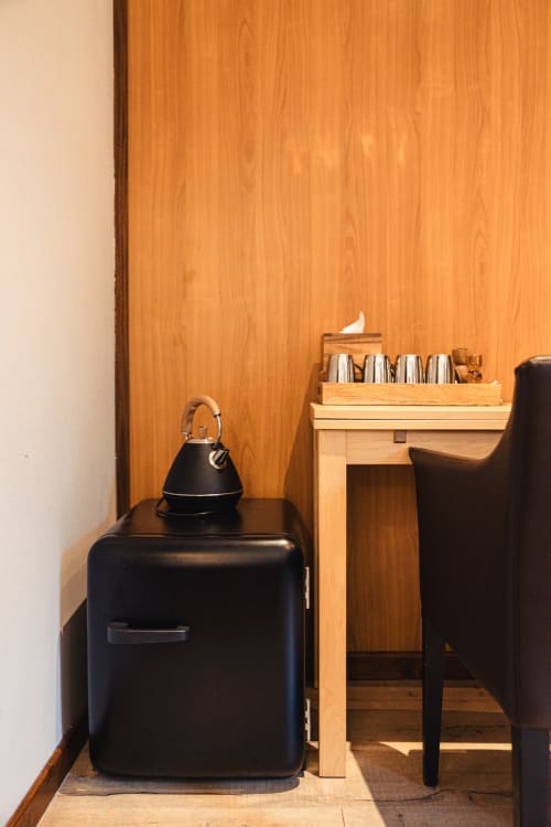 Coin de chambre d'hôtel moderne au Savoy avec bouilloire noire, bureau en bois avec service à thé et fauteuil en cuir noir