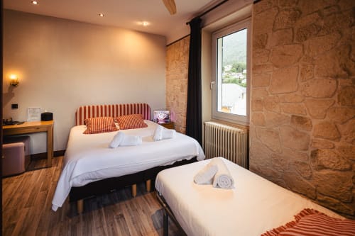 Chambre triple du Savoy Hôtel à Le Bourget-du-Lac avec murs en pierre, vue montagne et équipements modernes