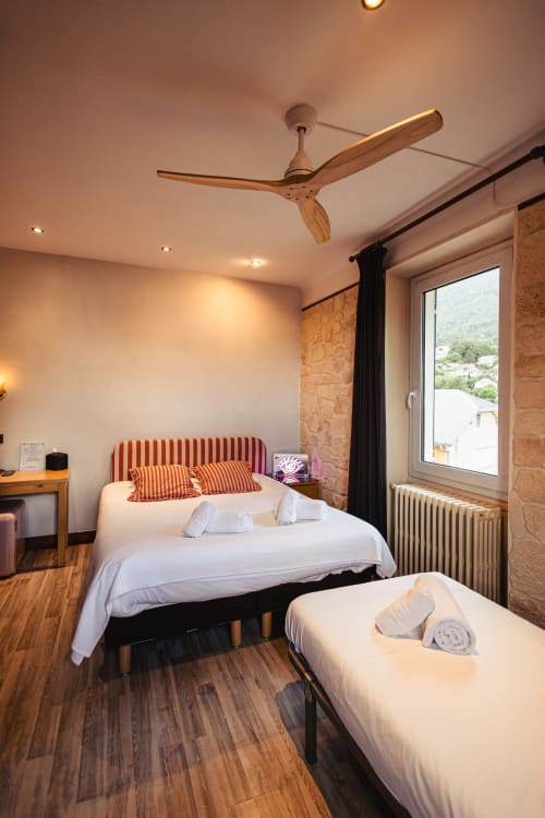 Chambre triple à l'Hôtel Savoy avec lit double, lit simple, vue montagne, ventilateur de plafond en bois et murs en pierre