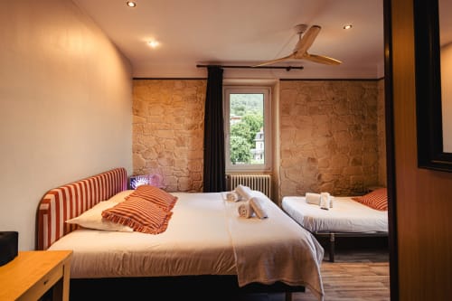Chambre triple au Savoy Hôtel du Bourget-du-Lac avec têtes de lit rayées, ventilateur de plafond en bois et murs en pierre