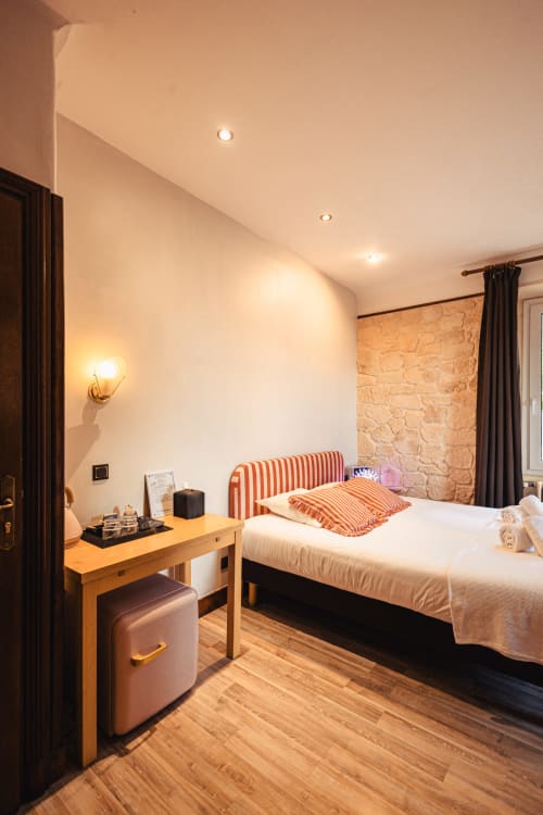 Chambre triple moderne au Savoy Hôtel avec tête de lit rayée, bureau en bois et mur en pierre