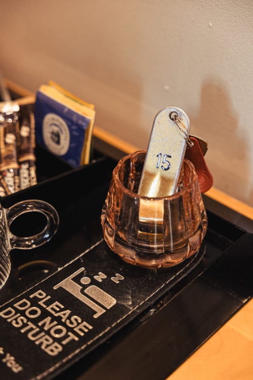 Cloche en cuivre numérotée 15 au Savoy Hôtel Le Bourget-du-Lac, détail élégant du service en chambre avec livre bleu et accessoires de bureau