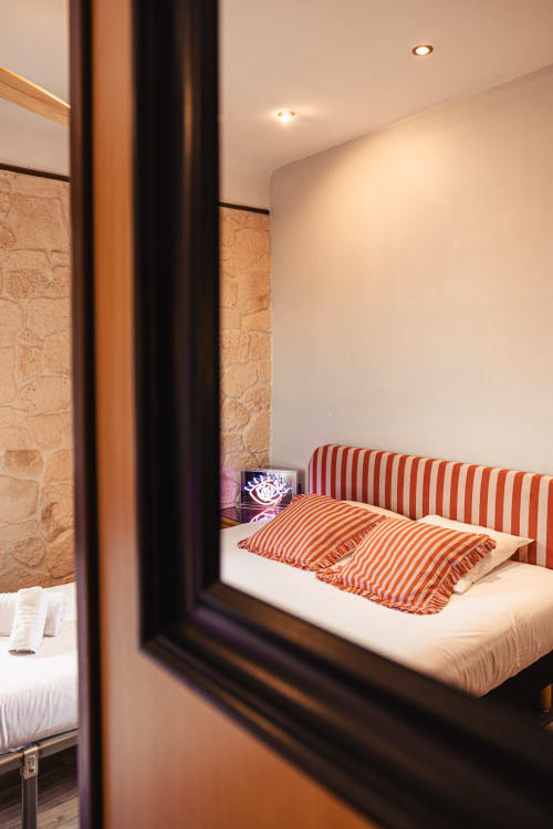 Chambre élégante du Savoy Hôtel avec oreillers rayés, mur en pierre et éclairage ambiant à Le Bourget-du-Lac