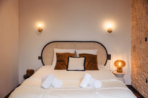Chambre double moderne au Savoy Hôtel avec tête de lit en rotin, appliques murales en laiton, linge blanc et coussins marron