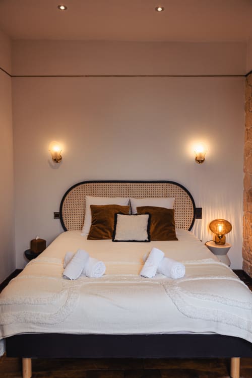 Chambre double de l'Hôtel Savoy avec tête de lit tissée, literie blanche, oreillers marron et éclairage mural ambiant au Bourget-du-Lac