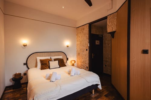 Chambre double moderne au Savoy Hôtel avec tête de lit en rotin, literie blanche, éclairage chaleureux et accents en bois au