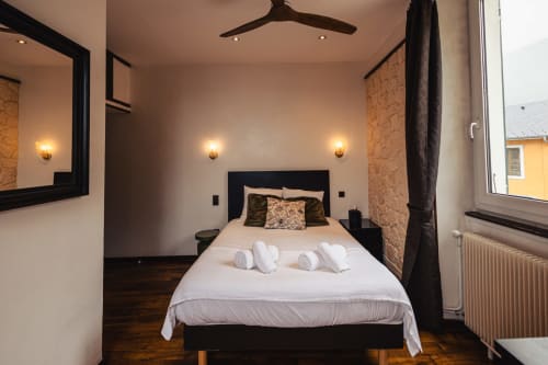 Chambre double moderne au Savoy Hôtel du Bourget-du-Lac avec lit noir, draps blancs, appliques murales et boiseries