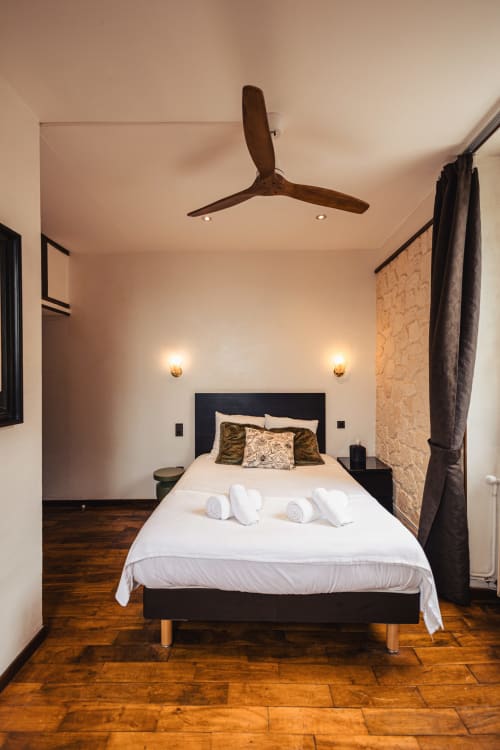 Chambre double contemporaine au Savoy Hôtel avec lit noir, linge blanc, parquet, ventilateur de plafond et éclairage ambiant