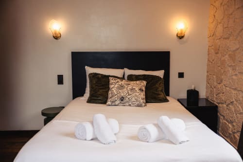 Chambre double luxueuse au Savoy Hôtel avec literie blanche impeccable, coussins décortatifs, serviettes roulées et éclairage ambiant