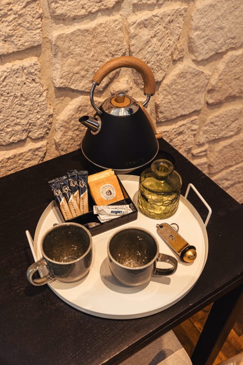 Service de bienvenue au Savoy Hôtel avec bouilloire noire, deux tasses, sachets de café et équipements sur plateau blanc sur pierre