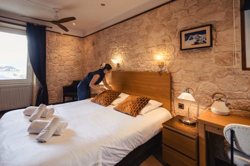 Chambre d'hôtel au Savoy Hôtel avec murs en pierre, lit en bois, draps blancs et vue sur les montagnes au Bourget-du-Lac