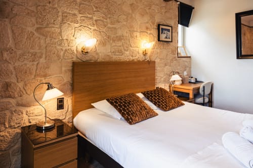 Chambre double du Savoy Hôtel au Bourget-du-Lac avec mur en pierre, tête de lit en bois et éclairage chaleureux