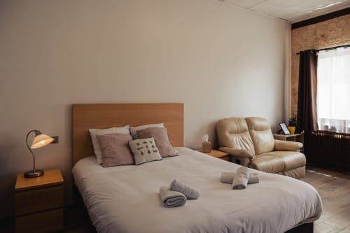 Chambre double moderne au Savoy Hôtel du Bourget-du-Lac avec lit en bois, fauteuil beige et vue sur les montagnes