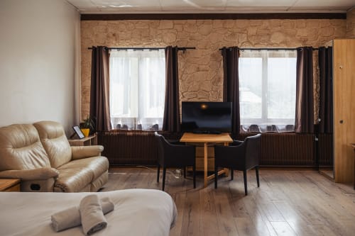 Spacieuse chambre double au Savoy Hôtel avec sièges en cuir beige, bureau en bois avec TV écran plat et vue sur les montagnes