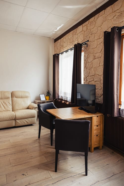 Chambre double moderne du Savoy Hôtel avec espace de travail, téléviseur écran plat, fauteuil en cuir et canapé crème au Bourget-du-Lac