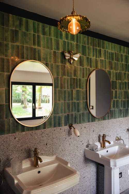 Salle de bains de l'hôtel Savoy à Le Bourget-du-Lac avec carrelage vert, double vasques sur piédestal et robinetterie en laiton