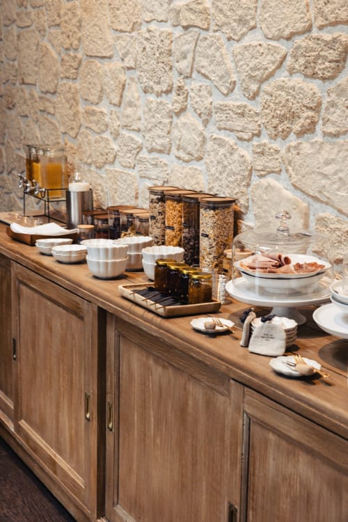 Buffet petit-déjeuner de l'hôtel Savoy avec mur en pierre, comptoir en bois, céréales, viennoiseries et couverts