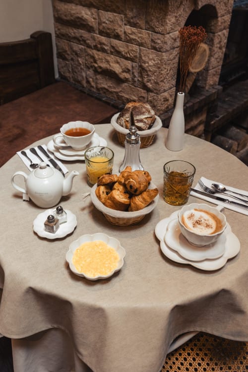 Élégant petit-déjeuner au Savoy Hôtel Le Bourget-du-Lac avec croissants, café, pâtisseries et boissons sur nappe en lin