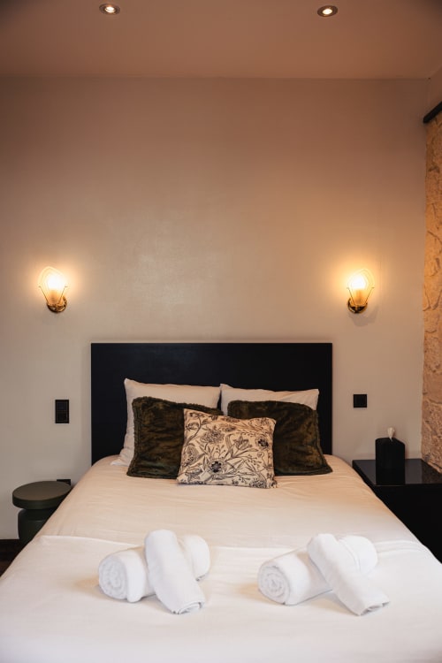 Chambre de luxe au Savoy Hôtel avec tête de lit noire, literie blanche, appliques murales dorées et serviettes roulées