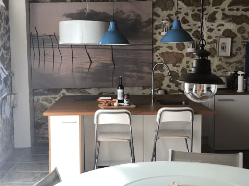 Cuisine moderne avec comptoir en bois, suspensions bleues et vue sur la mer dans un appartement à Palafrugell
