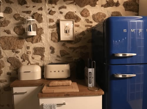 Réfrigérateur bleu SMEG rétro et appareils électroménagers crème dans la cuisine d'un appartement à Palafrugell avec mur en pierre
