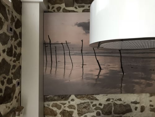 Œuvre d'art paysage plage encadrée dans appartement Palafrugell montrant poteaux en bois reflétés sur sable mouillé au coucher du soleil