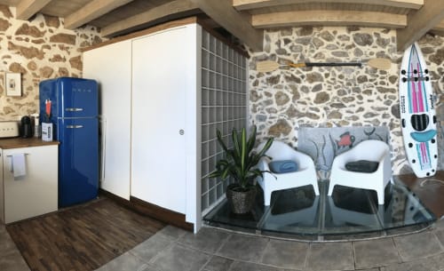 Appartement moderne à Palafrugell avec murs en pierre, kitchenette, réfrigérateur bleu rétro et coin détente en bord de mer avec planche de surf