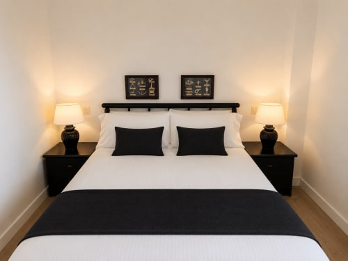 Dormitorio moderno en blanco y negro del apartamento As Estelas en Baiona, con acceso a balcón con vistas al mar y mobiliario contemporáneo