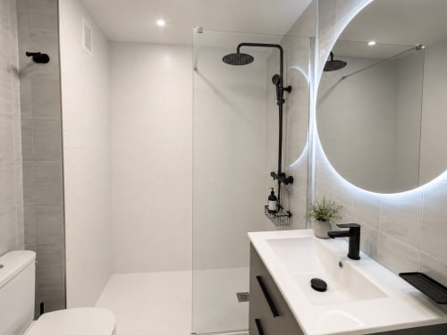 Baño moderno del apartamento As Estelas en Baiona con ducha abierta, espejo iluminado y accesorios negros