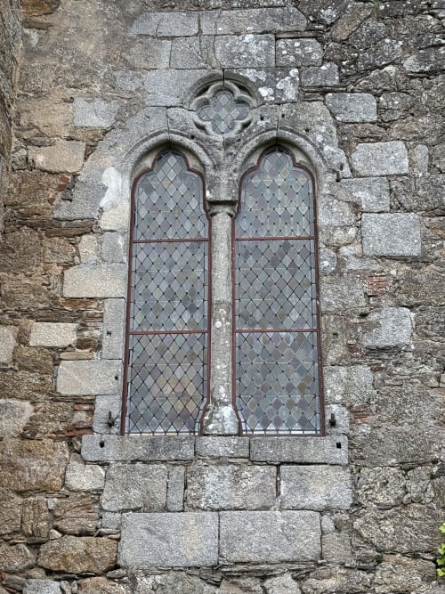 Mur en pierre médiéval avec deux fenêtres en arc et grillage en fer au Domaine de Châlus-Chabrol, Châlus