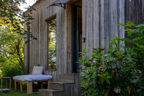 Cabane perchée en bois aux Cabanes de Julie avec transat sur la terrasse, entourée de verdure