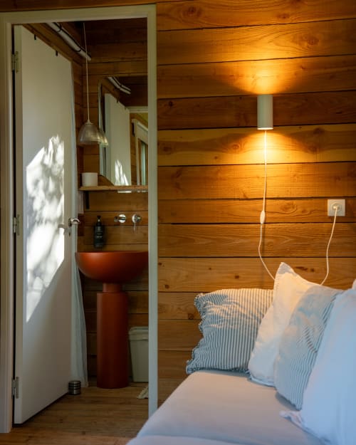 Chambre douillette en bois aux Cabanes de Julie avec salle de bain attenante, lit aux oreillers rayés et éclairage ambiant chaleureux