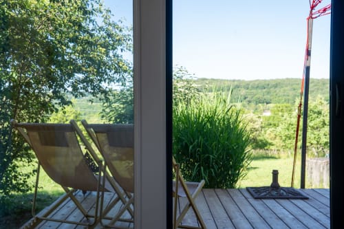 Vue sur la terrasse des Cabanes de Julie avec chaises longues dominant les jardins de la vallée luxuriante et les collines boisées