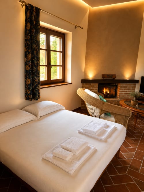 Cozy hotel room at Agriturismo Colle Mura with fireplace, garden view window, and warm ambient lighting