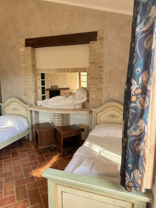 Camera Ulivo presso Agriturismo Colle Mura con letti gemelli, arredi crema e verde, e vista sul giardino a Gualdo Tadino