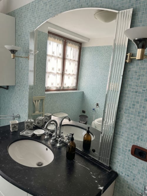 Bagno con piastrelle azzurre, lavabo bianco, piano nero e finestra all'Agriturismo Colle Mura
