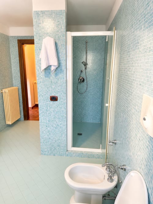 Bagno moderno con piastrelle a mosaico azzurre, lavabo con piedistallo bianco e doccia aperta presso Agriturismo Colle Mura, Gualdo