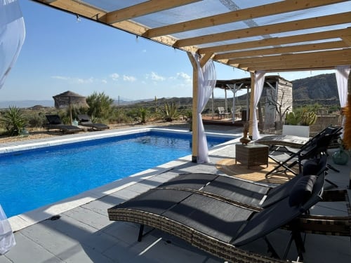 Lujosa zona de piscina en El Sueño de Andalucia con tumbonas, pérgola de madera y vistas a las montañas en Huércal-Overa