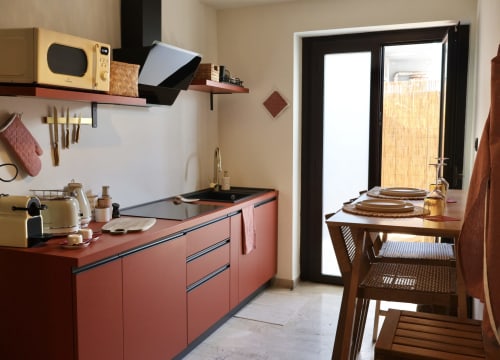 Cucina moderna compatta con cabinetry color corallo, zona pranzo e porte vetrate verso il balcone di Tagasuites, Catania
