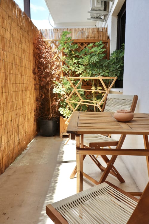 Terrazza soleggiata con tavolo in legno, sedie e piante in vaso presso l'apartment Tagasuites a Catania