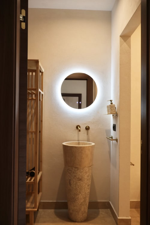 Bagno moderno di Tagasuites Catania con specchio circolare illuminato e lavabo in pietra