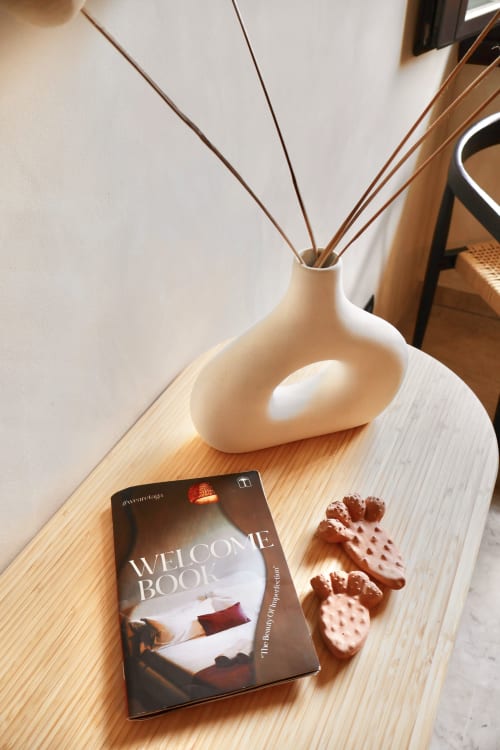 Accogliente setup appartamento Tagasuites Catania con welcome book, diffusore di aromi e pasticcini su tavolo in legno