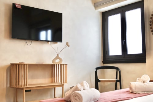 Camera moderna presso Tagasuites Catania con TV a parete, mobili in legno e arredamento minimalista