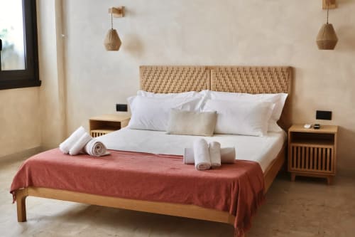 Camera da letto moderna a Catania con testata intrecciata in legno, biancheria bianca, plaid color corallo, lampade sospese