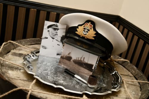 Naval officer photo and white captain's hat with gold insignia displayed on decorative tray in The Lower Deck apartment at