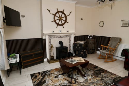 The Lower Deck apartment at Love Short Stays features nautical-themed living room with ship's wheel decor, fireplace, wooden