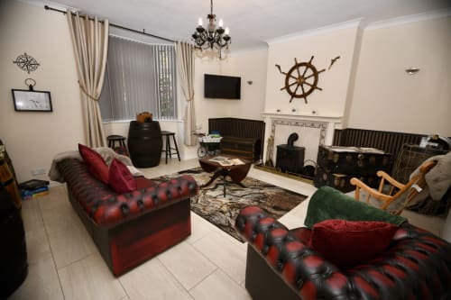 The Lower Deck apartment at Love Short Stays features red chesterfield sofas, nautical decor, fireplace, and garden views in